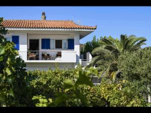 a white house with a balcony and a palm tree at Pipina's Beach Apartment in Fanari