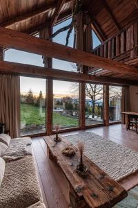 uma sala de estar com uma mesa de madeira e janelas grandes em Chata Pytlorka Beskydy offgrid wellness em Zahŭří