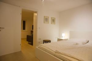 Un dormitorio blanco con una cama y una silla. en Vogelsang Apartments, en Gmunden