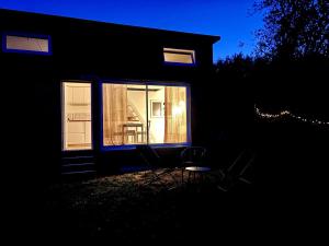 a house with a window and a chair in the dark at Tiny House cosy in Saint-Sylvain-dʼAnjou