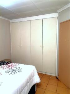 a bedroom with white cabinets and a bed at M Gold Apartments in Pretoria