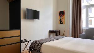 a hotel room with a bed and a flat screen tv at Tesouro da Baixa by Shiadu in Lisbon