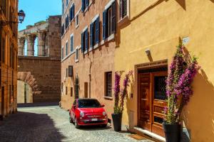 a red car parked in an alley with buildings at The Inn at the Roman Forum Luxury Collection - The Inn At The Roman Forum in Rome