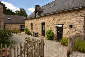 een stenen gebouw met een houten hek ernaast bij Gîtes calmes écologiques in Saint-Symphorien
