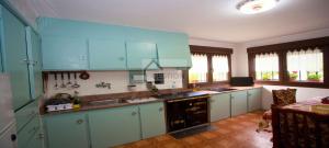 eine große Küche mit blauen Schränken und einem Tisch in der Unterkunft Villa Teresa in Cangas de Onís