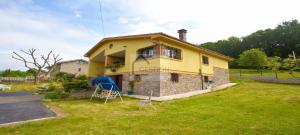 ein gelbes Haus mit zwei Stühlen im Hof in der Unterkunft Villa Teresa in Cangas de Onís