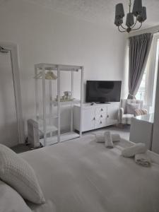 a white bedroom with a bed and a tv at Southcliffe hotel in Bridlington +6 photos