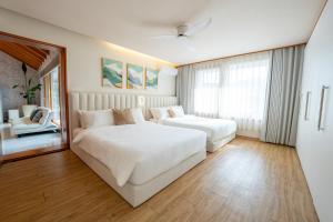 ein weißes Schlafzimmer mit 2 Betten und einem Stuhl in der Unterkunft Bs Urban Retreat Garden And Spa Near Gyeongbokgung in Seoul