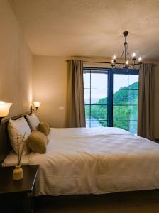 a bedroom with a large bed and a large window at Domeniul Caprioara in Căprioara
