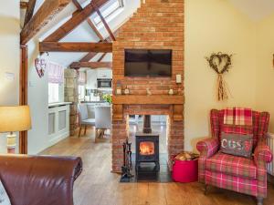 a living room with a brick fireplace and a tv at Cowslip Cottage in Swarland