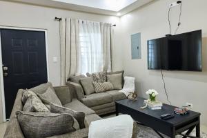 a living room with a couch and a tv on a wall at Blanket Brew Accommodation in Bacolet