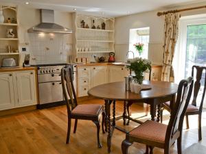 eine Küche mit Tisch und Stühlen und einem Herd in der Unterkunft Grooms Cottage in Westleigh