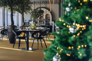 a christmas tree in a restaurant with tables and chairs at MERICI Hotel Sittard in Sittard +66 photos
