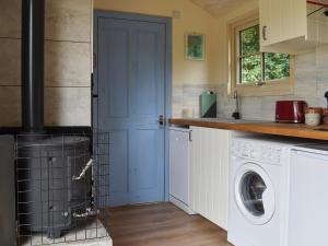 a kitchen with a washing machine and a blue door at The Shepherd's Hut in Herstmonceux
