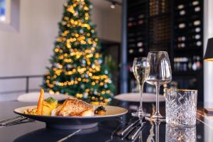 a table with a plate of food and a christmas tree at MERICI Hotel Sittard in Sittard