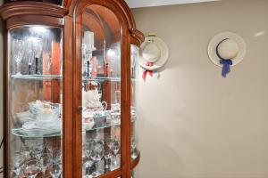 Ein Holzschrank voller Geschirr und Hüte an einer Wand in der Unterkunft Cozy Retreat with Hot Tub in Peaceful Goshen home in Goshen + 23 Fotos