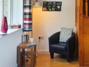 a living room with a chair and a table at Stabl-Oh4 in Dihewid