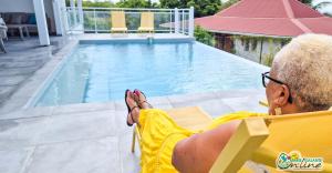 una donna seduta su una sedia accanto alla piscina di Villa Outaouais a Bielle Altre 6 foto