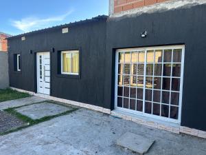 a black building with two windows and a white door at Quinta descansar in Concepción del Uruguay