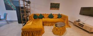 a living room with a yellow couch with green pillows at Azizi Luxury Apartments - Beach Pool & Spa Resort in Mamaia Nord