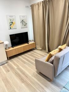 a living room with a couch and a flat screen tv at Central Studio – Flor De Sol in Tavira