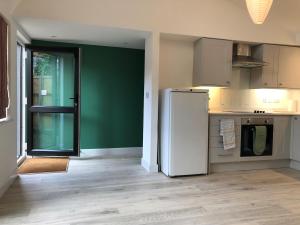 een keuken met een witte koelkast en een groene muur bij Perfitt Place in Bungay