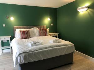 een slaapkamer met een groot bed met groene muren bij Perfitt Place in Bungay