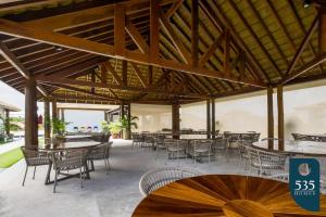 an outdoor patio with tables and chairs and a large wooden ceiling at Praia do Forte 2 bedrooms Complete and Comfortable in Mata de Sao Joao
