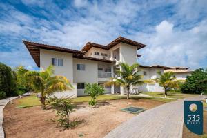 a house with palm trees in front of it at Praia do Forte 2 bedrooms Complete and Comfortable in Mata de Sao Joao