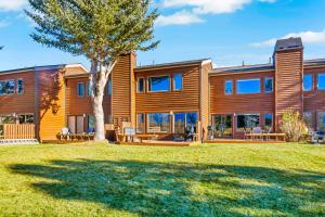a large wooden house with a tree in the yard at Glacier D in Teton Village