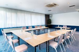 a conference room with long tables and chairs at Holiday Inn - the niu, Stream Mönchengladbach by IHG in Mönchengladbach