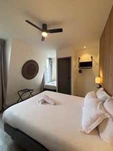 a bedroom with a large white bed with a ceiling fan at Korner République in Paris