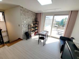 a living room with a table and chairs and a glass door at Stay by J in Jeju