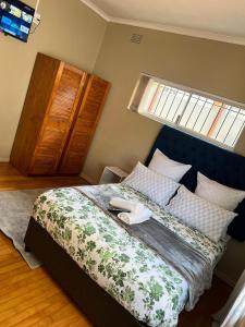 a bedroom with a bed with a blue headboard and a window at Ridah's Accomodation in Bellville