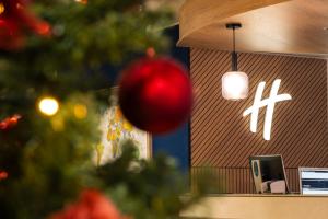 Uma árvore de Natal em frente a uma loja com um enfeite natalino. em Holiday Inn Eindhoven Centre by IHG em Eindhoven