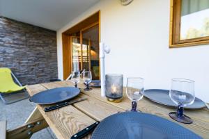 a wooden table with plates and glasses on it at Bel Appartement lumineux au coeur de la station de Vars in Vars