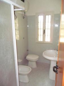 a white bathroom with a toilet and a sink at Canto delle Rane in Vieste