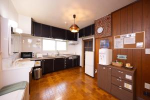 a kitchen with black cabinets and a white refrigerator at 空彩 -sorairo2- 札幌と富良野のまんなか in Mikasa
