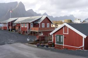 a row of red houses with mountains in the background at Rostad Retro Rorbuer in Reine