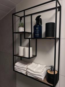 a black shelf with towels and toiletries in a bathroom at Green Garden Oslo - Luxury Resort in Kolbotn +63 photos