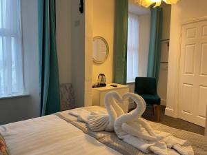 - deux serviettes de cygne assises sur un lit dans l'établissement Tintagel Arms Bed and Breakfast, à Tintagel