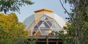 韦尔卡鲍Capão Domo的一座建在树木环绕的建筑物顶部的玻璃房