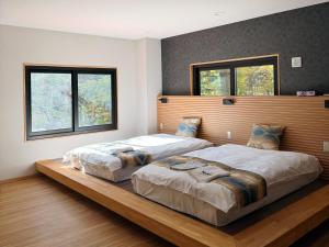 two beds in a bedroom with two windows at 苗場サンバレーホテル in Minami Uonuma