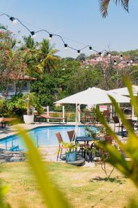 a swimming pool with tables and chairs and an umbrella at Pousada Tajupá in Pirenópolis +30 photos