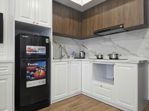 a kitchen with a black refrigerator and white cabinets at Hoa Đảo Vua in Binh Hai