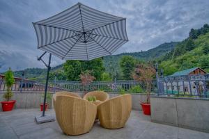 a patio with two chairs and an umbrella at Mountain Nest A Boutique Stay Near Dal Lake, Srinagar in Srinagar +12 photos