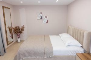 a white bedroom with a bed and a mirror at 3 Min To Center Stylish Stay's in Tirana