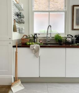 a kitchen with white cabinets and a sink and a window at Cresswell Lodge in Richmond