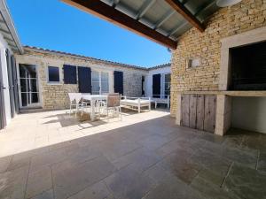 eine Terrasse mit Tisch und Stühlen und einer Backsteinmauer in der Unterkunft Maison 5 chambres jusqu'à 10 pers - Proche Phare des Baleines - FR-1-835-17 in Saint-Clément-des-Baleines