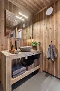 ein Badezimmer mit einem Waschbecken und einer Holzwand in der Unterkunft Large family cabin at Hafjell with ski in-ski out in Hunder